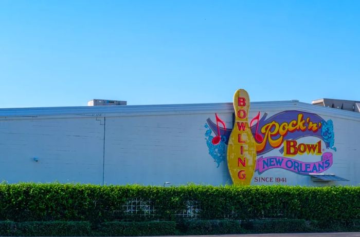 Sign for Rock 'N' Bowl, a bowling alley and live music venue, set against a white building