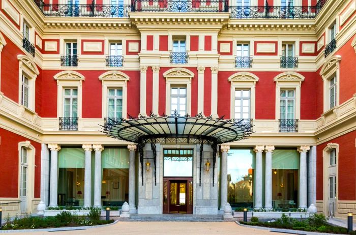 The red and beige neoclassical façade of Hôtel du Palais in Biarritz, France.