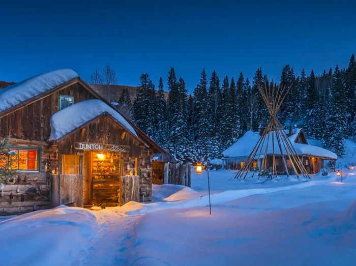 Nighttime exterior view of Dunton Hot Springs cabins blanketed in snow.