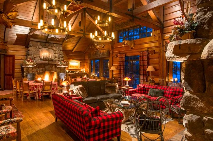 The spacious wooden room at The Point features buffalo plaid couches, elegant chandeliers, and cozy stone fireplaces, creating an inviting atmosphere.