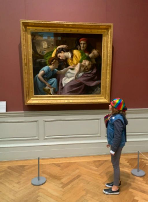 Maya, sporting a holographic cap, contemplates a painting at the Met.