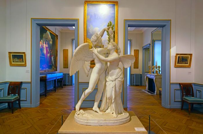 A white statue of Cupid and Psyche surrounded by impressionist artworks at the Musée Marmottan-Monet.