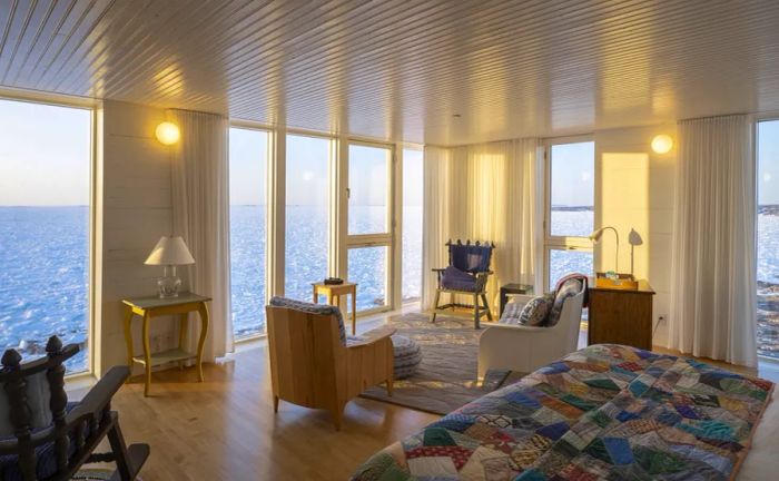 This suite at Fogo Island Inn boasts expansive floor-to-ceiling windows offering stunning ocean views and a bed adorned with a handmade quilt.