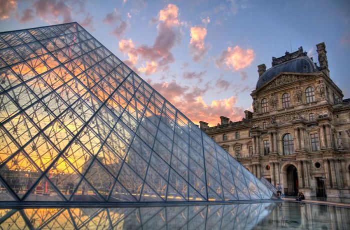 The Louvre's iconic structure set against the glass pyramid in the courtyard at dawn.