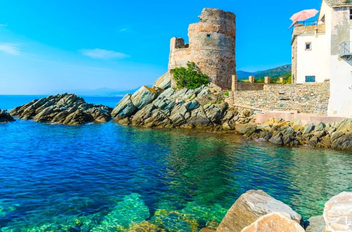 Shallow cove off Corsica, with old stone buildings in the background