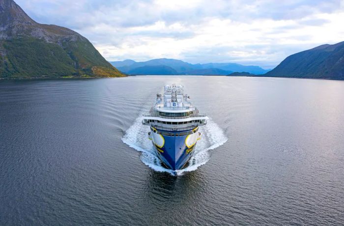 The National Geographic Resolution, operated by Lindblad, is elegantly nestled in a scenic waterway framed by rolling hills.