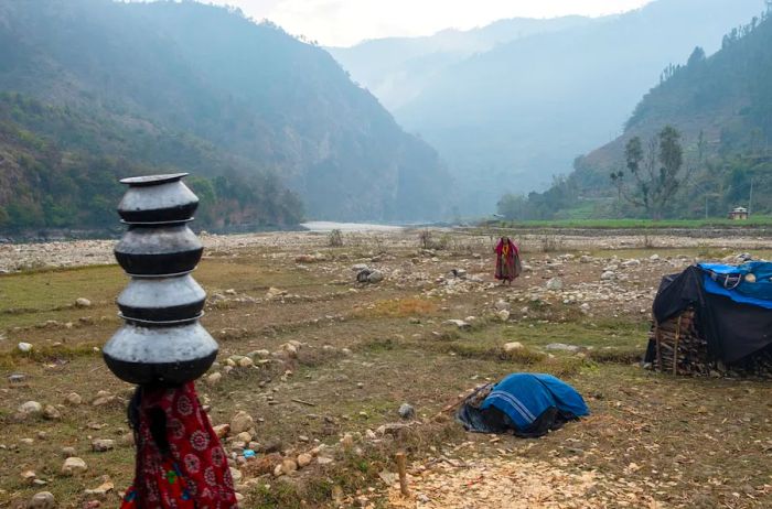 A Raute woman balances a stack of bowls on her head.