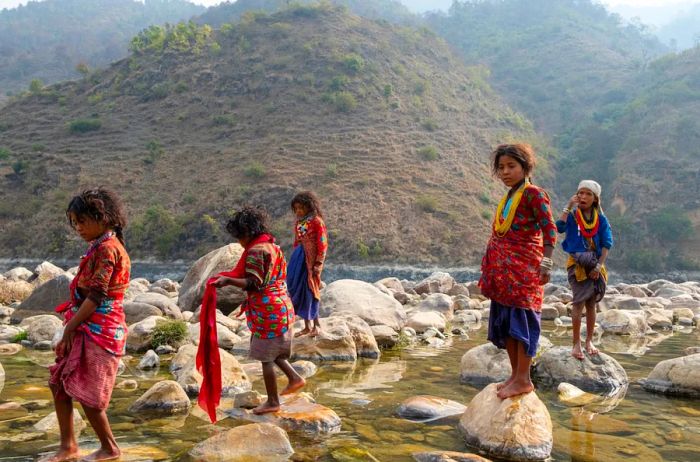 Raute children are seen playing in a river in Nepal.