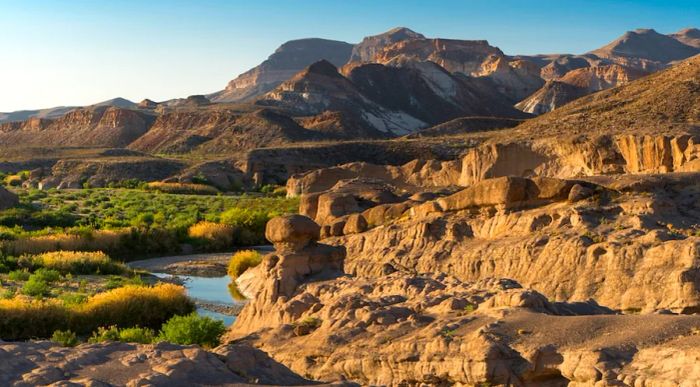 Brown rock formations alongside a river.