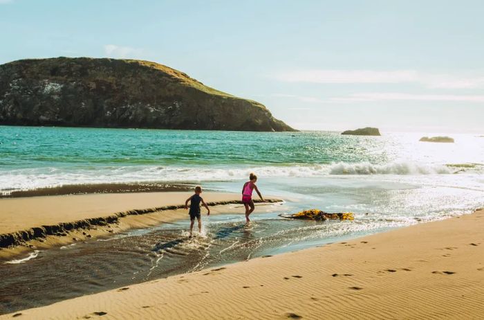 Two children playing in the water near a beach.