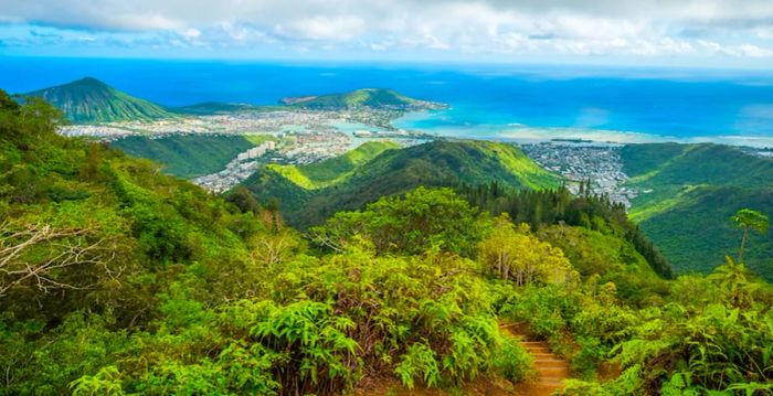 A clear blue sky above lush green mountains along the Kuliouou Ridge Trail in Oahu, Hawaii.