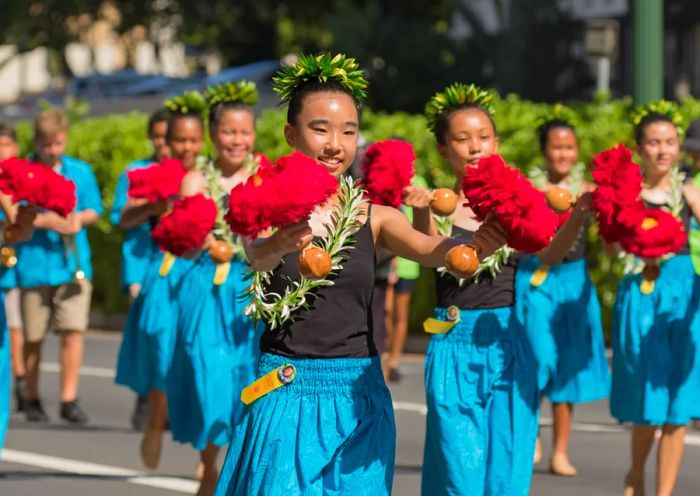 Hula dancers parading down a street.