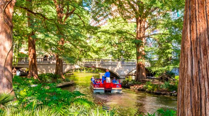 A small boat drifting along a tree-lined river in San Antonio