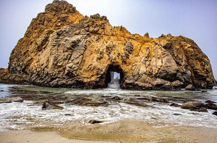 A prominent offshore rock featuring a small cave, known as Keyhole Arch, at Pfeiffer Beach