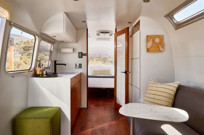 Inside one of the trailers at AutoCamp Zion, you'll find a kitchenette, a cozy living room sofa, and a door leading to the bedroom in the background.