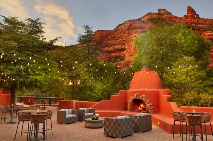 Terracotta-hued fireplace on the deck at Enchantment Resort in Sedona, with stunning red rock formations in the backdrop.