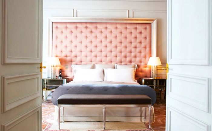 A guest room at Le Royal Monceau, Raffles in Paris features a bed set against a pink tufted headboard.