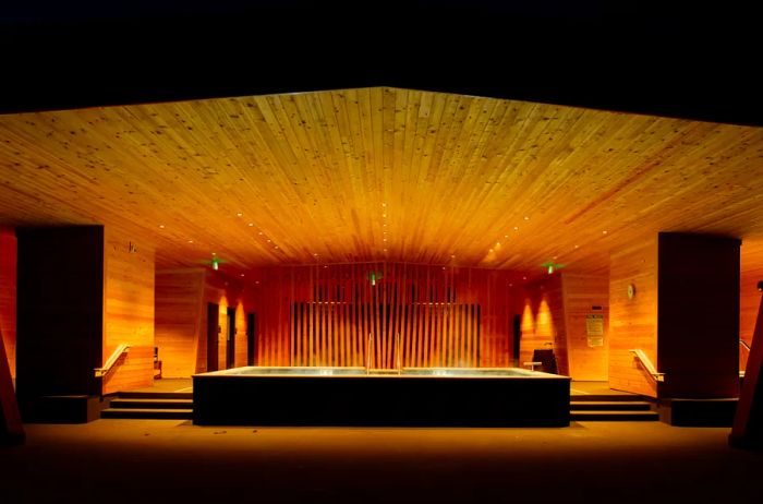 An intimate outdoor soaking pool beneath a wooden pavilion at night