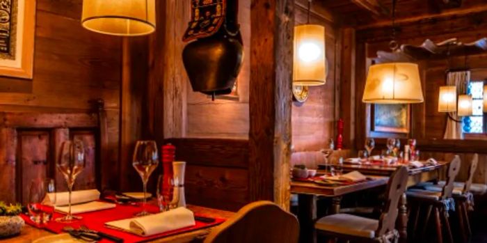 The Swiss Stübli restaurant at the Alpina Gstaad boasts rustic wooden walls and pillars, offering traditional Swiss dishes like fondue and raclette.