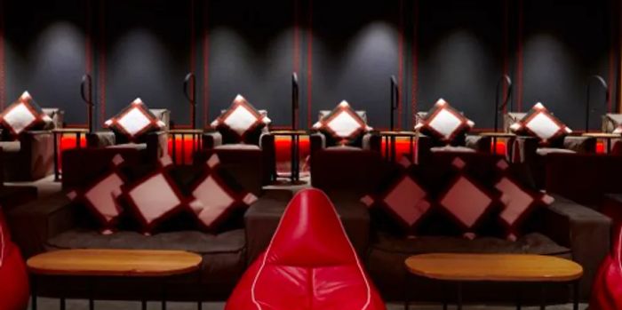 The private cinema at the Alpina Gstaad features a stylish black and red decor complemented by oversized sofas.