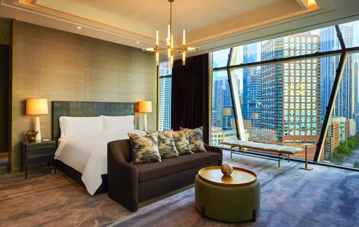 Inside a guest room at the St. Regis Chicago, enjoy the comfort of a brown sofa and stunning city views through floor-to-ceiling windows.