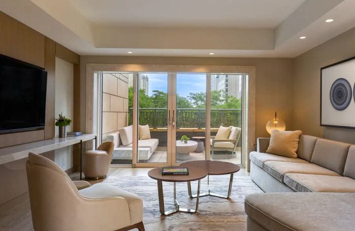 The interior of a beige Water Tower Terrace Suite at the Park Hyatt Chicago, featuring tall glass doors that open to a private balcony.