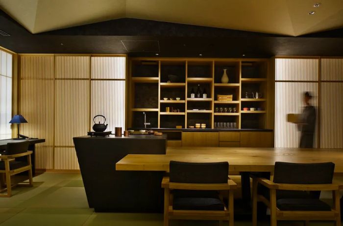 The ochanoma lounge at Hoshinoya Tokyo boasts a large wooden table surrounded by chairs, with shelves filled with teapots, teacups, and an array of snacks.