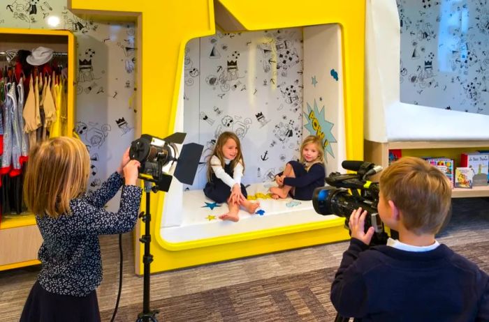 Two children recording a video of their friends in an indoor studio.