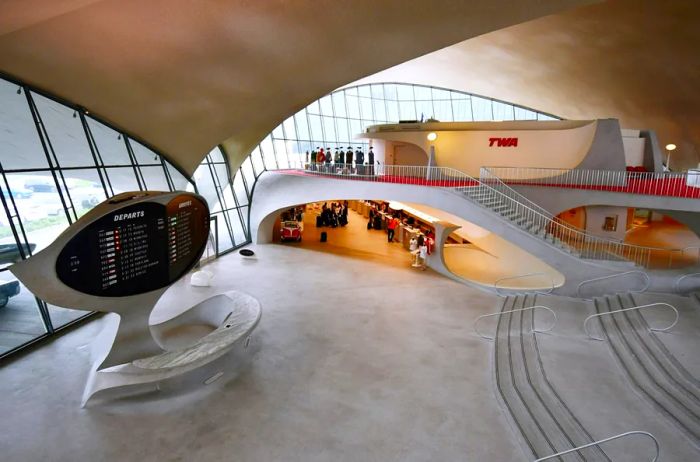 The spacious, flowing white lobby of the TWA Flight Center, designed by Eero Saarinen, has been transformed into the TWA Hotel.