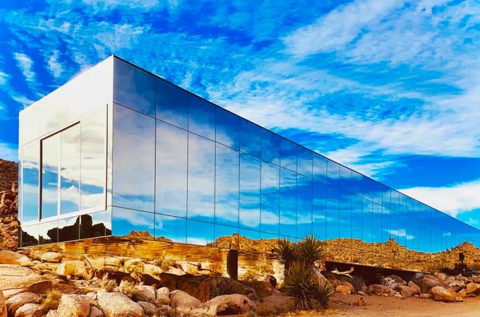 The rectangular glass structure known as the Invisible House in Joshua Tree is crafted to seamlessly integrate with the desert landscape.