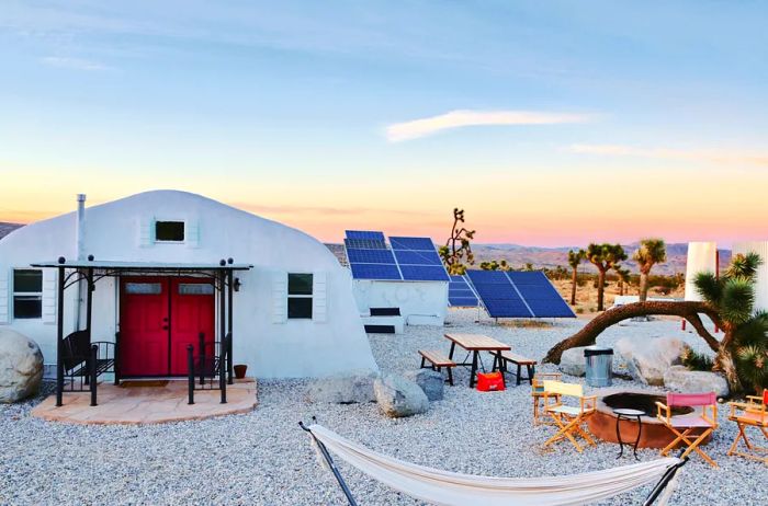 The exterior of a sleek white dome house featuring a hammock