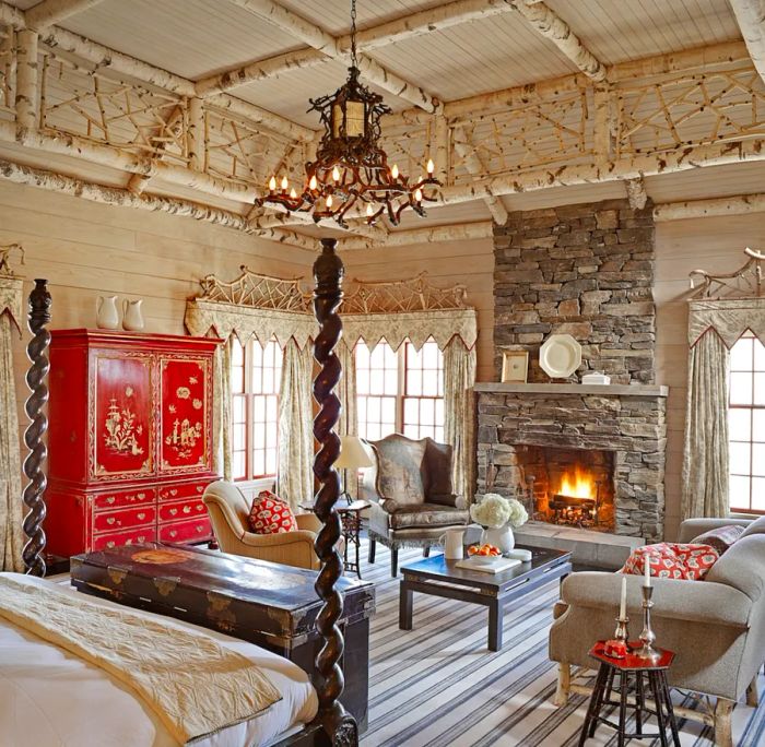 This guest room in the Timber Camp cottage at Twin Farms in Vermont features a red armoire, a four-poster bed, and a stunning chandelier.