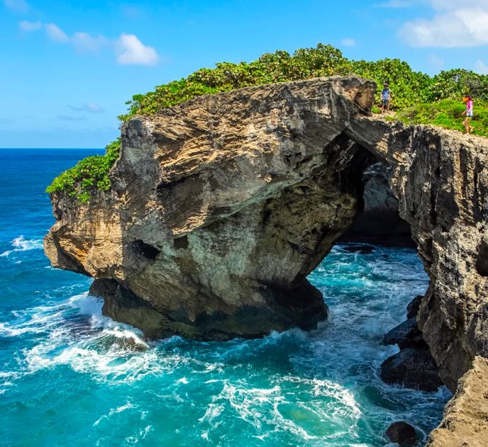 A view of Cueva del Indio, a coastal cave in Arecibo, Puerto Rico, set against the backdrop of bright blue waters during the day.