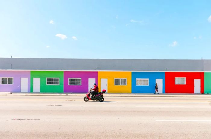 A solitary red motorcycle cruises past a row of colorful houses in Little River.