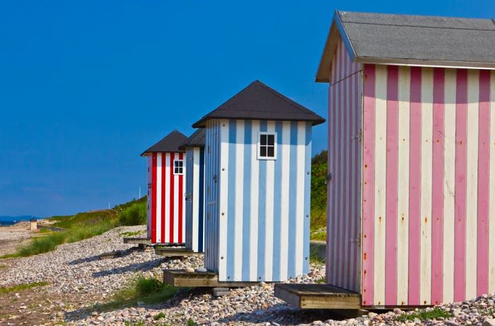Colorful beach huts with vertical stripes on a pebble shore