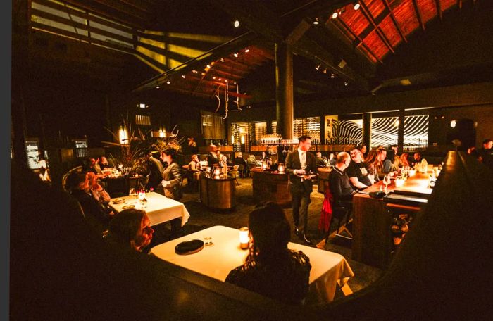 Guests enjoying an intimate ambiance in a dimly lit room adorned with candlelit tables