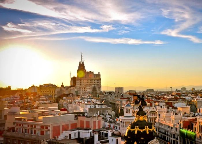Aerial view of Madrid, featuring building rooftops illuminated by the sunset