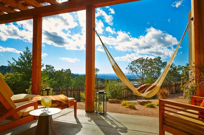 A wooden suite patio at the Four Seasons Resort Rancho Encantado Santa Fe, featuring two chairs and a hammock.