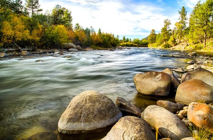Rugged boulders and trees lining a riverbank