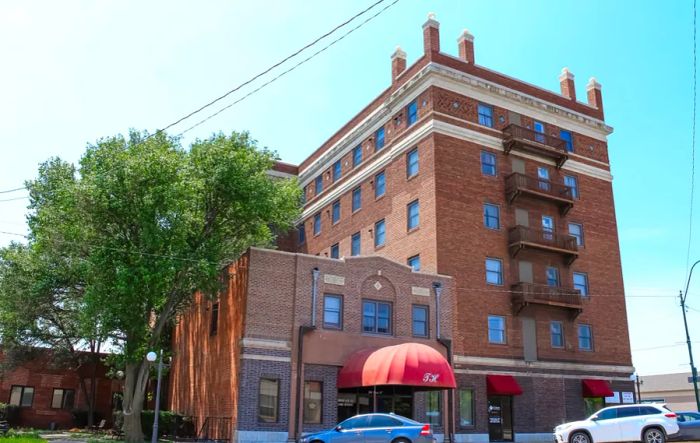 Two red-brick structures, with several cars parked in front of them.