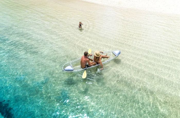 Aerial view of two people in a small paddleboat in shallow waters