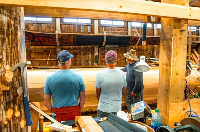 Artist Christian White (right) discusses the dugout canoe he is in the process of carving.