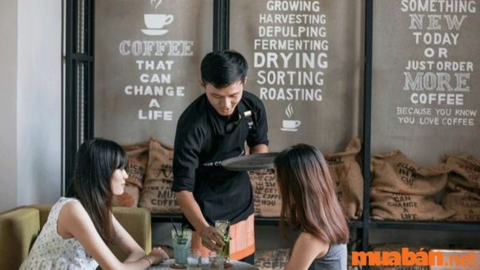 Nhân viên phục vụ quán cafe mang đồ đến bàn cho khách
