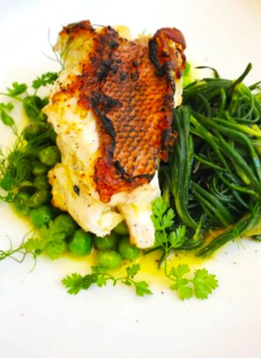 A vibrant dish of fresh fish atop a bed of sweet peas and samphire (sea beans) at Linou Soumpasis k sia.