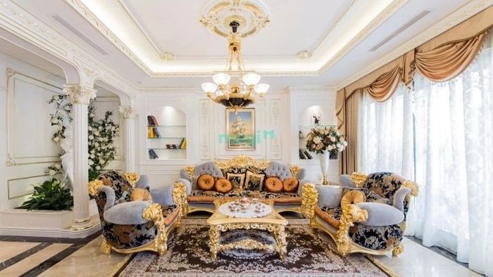 Đồ nội thất mạ vàng nổi bật trên nền tường trắng, tạo điểm nhấn cho phòng khách biệt thự