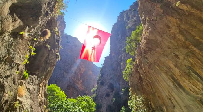 A massive Turkish flag flutters proudly at the entrance to the gorge.