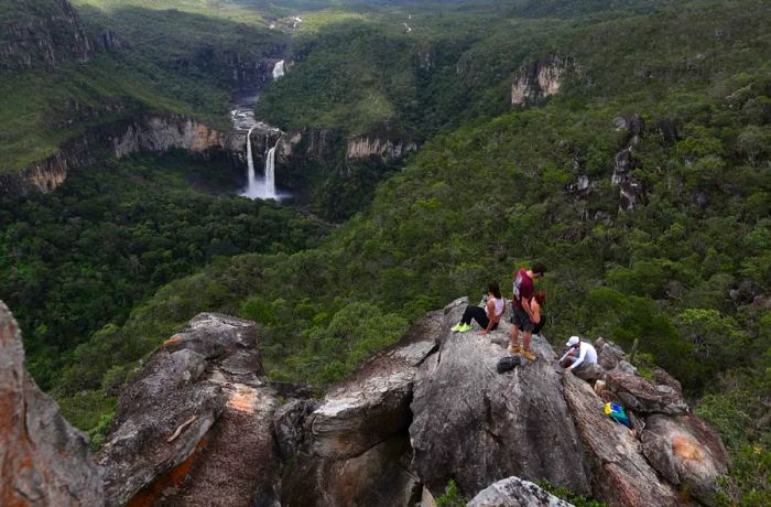 Visitors take a break on a rock formation by the Saltos do Rio Preto waterfall in Chapada dos Veadeiros.