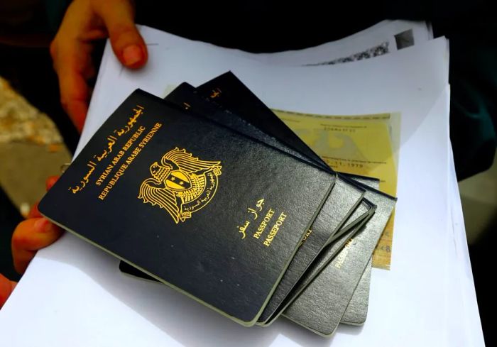 A refugee holds Syrian passports while waiting in line to apply for immigration outside the German Embassy in Beirut in 2015.