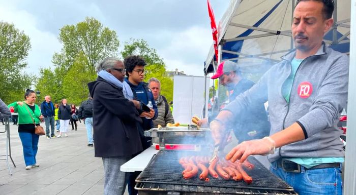 Ibrahim Lamhin, a grill cook for the labor union Force Ouvrière, grilling sausages at a protest in central Paris.