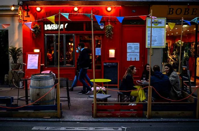 People enjoy drinks while sitting on a bar terrace in Paris on October 3, 2020.